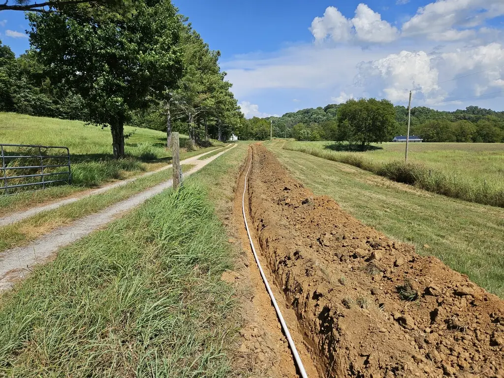 A long line of irrigation pipe laid out on a lawn in Spring Hill, TN, ready to be covered as part of an irrigation installation by Cutting Edge Lawn and Landscapes.