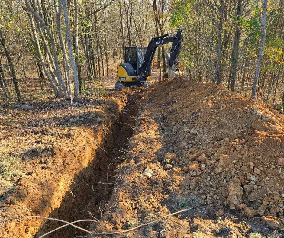 Workers digging a trench in a lawn to install buried electrical cables.