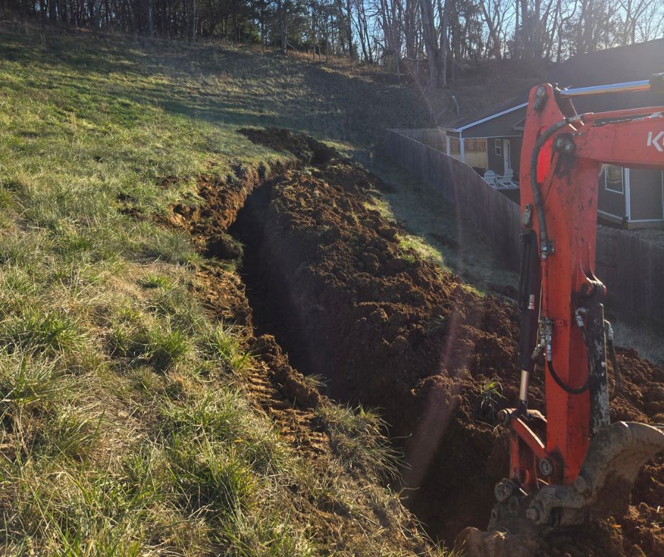Cutting Edge Lawn and Landscapes crew installing a drainage ditch using heavy equipment on a steep slope behind homes in Columbia, Tennessee.